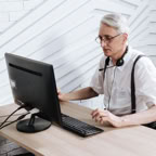 Senior adult man working in a call center with a headset and computer.