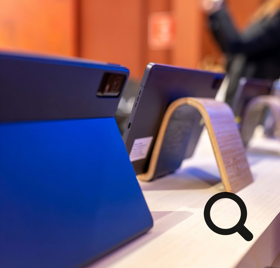 Close-up view of modern tablets on display in an electronics store with blurred customer.