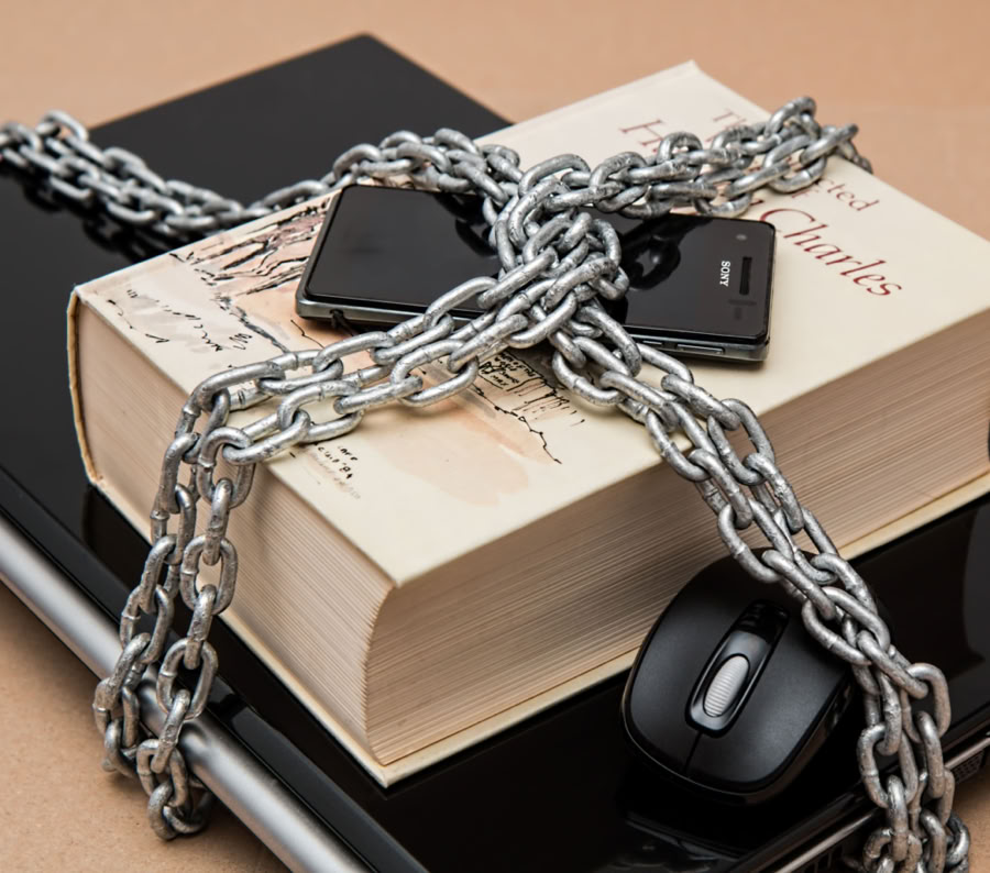 Chain-locked book, phone, and laptop symbolizing digital and intellectual security.